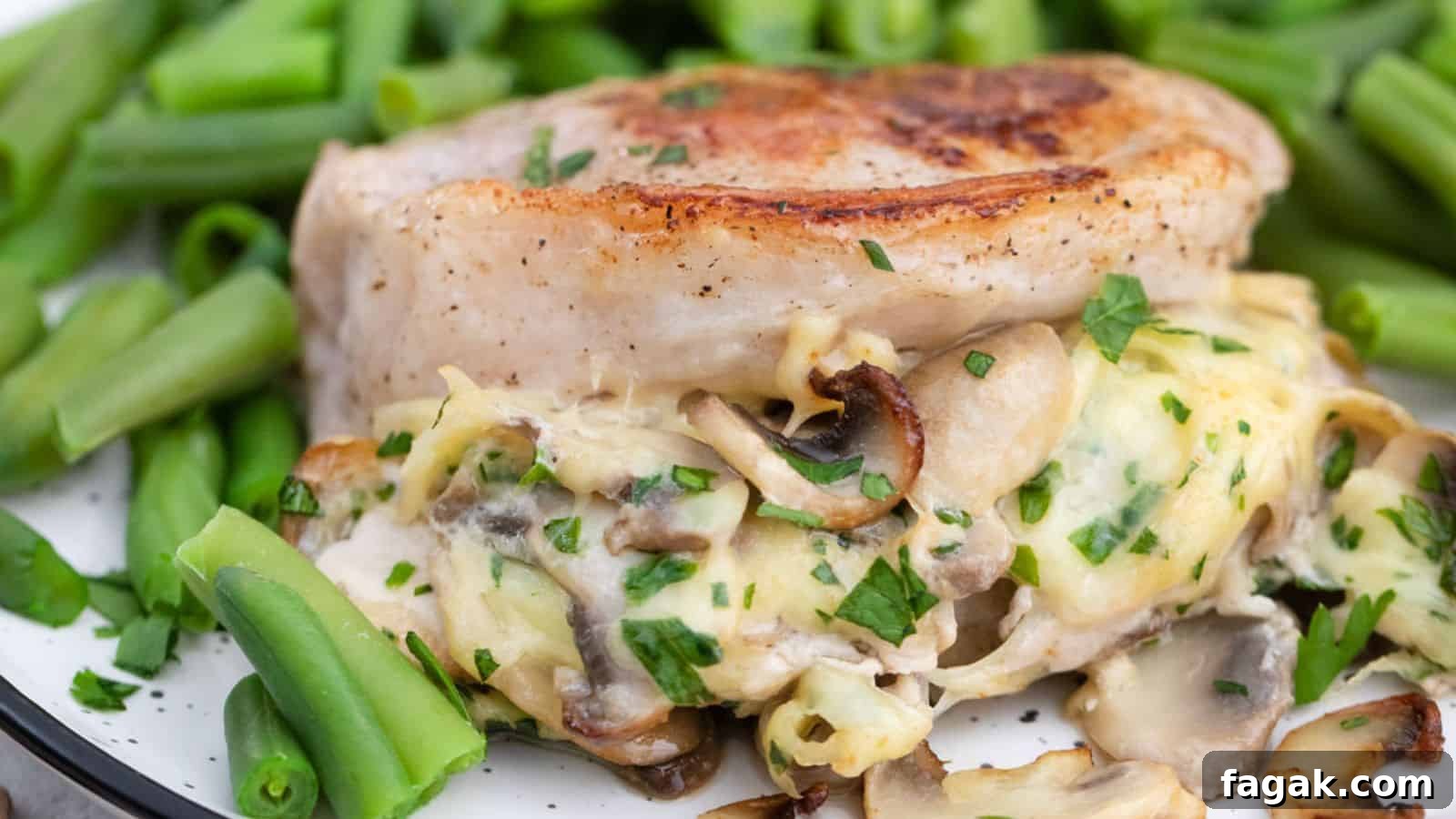 A plate of pork chops stuffed with mushrooms and cheese served with green beans.