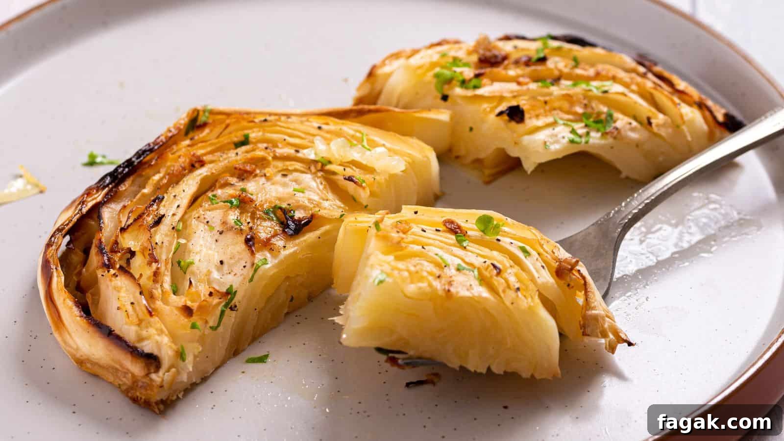 Sliced and roasted cabbage wedges seasoned with herbs on a white plate, garnished with black pepper and fresh herbs.