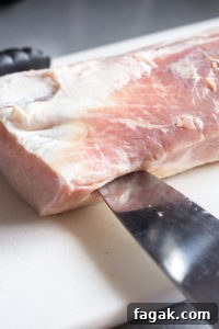 a large knife cutting into the edge of a pork roast