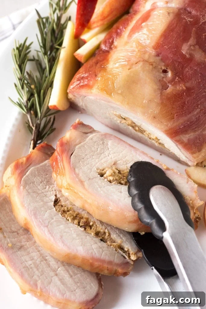 a pair of tongs taking a slice of smoked pork loin roast