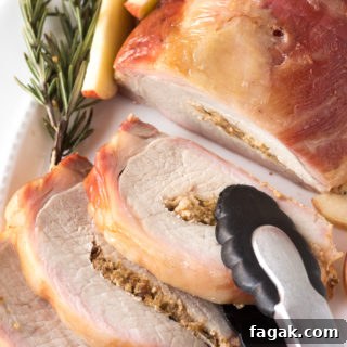 a pair of tongs taking a slice of smoked pork loin roast