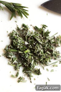 chopped rosemary on a white cutting board