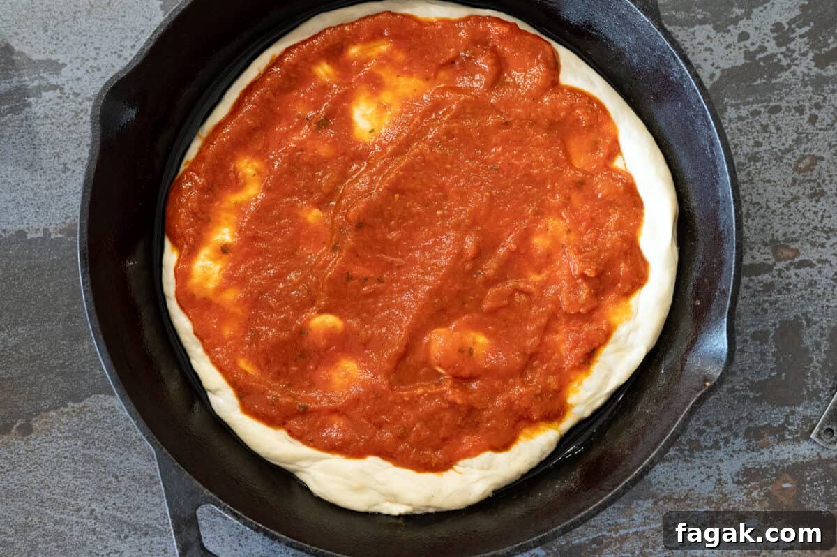 pizza dough in skillet with sauce.