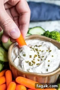 Hand dipping a carrot into dip.