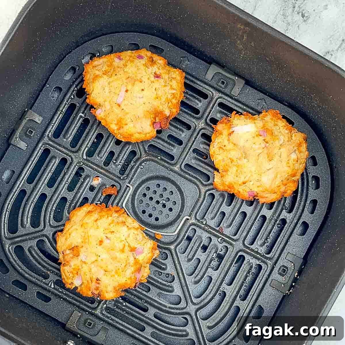 The golden brown air-fried tuna patties in the air fryer basket.