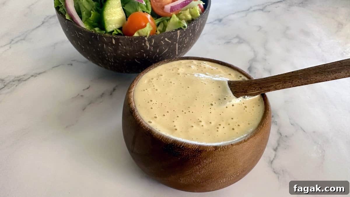 5-Minute Vegan Caesar Dressing Recipe: Creamy Plant-Based Dressing 2 Vegan Caesar dressing recipe in a bowl with a spoon with a salad behind it,