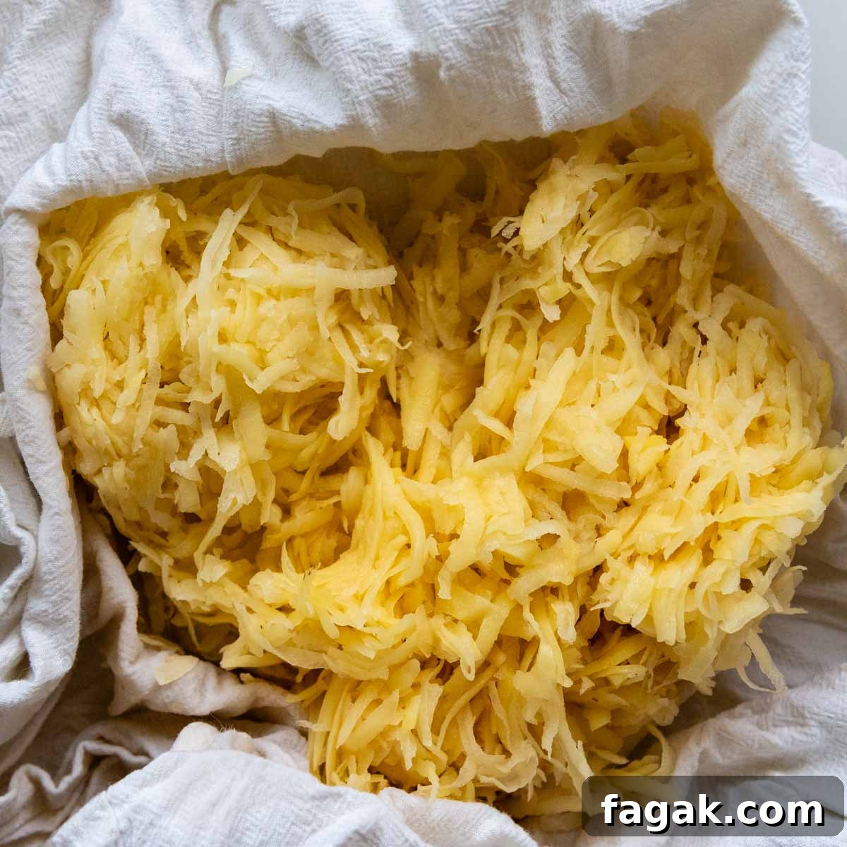 close up of raw grated potatoes in a flour sack towel 