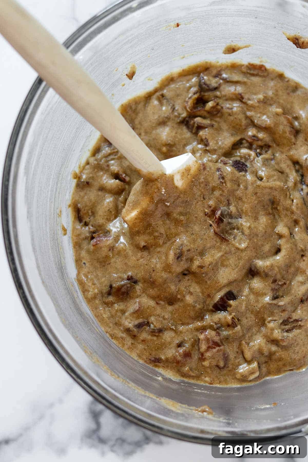 Date cake batter in a glass bowl with a spatula.