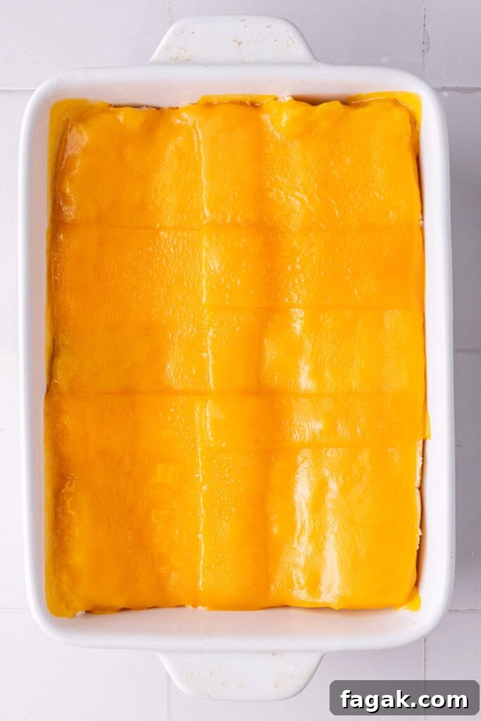Thin layer of melted cheese over bottom half of Hawaiian rolls.