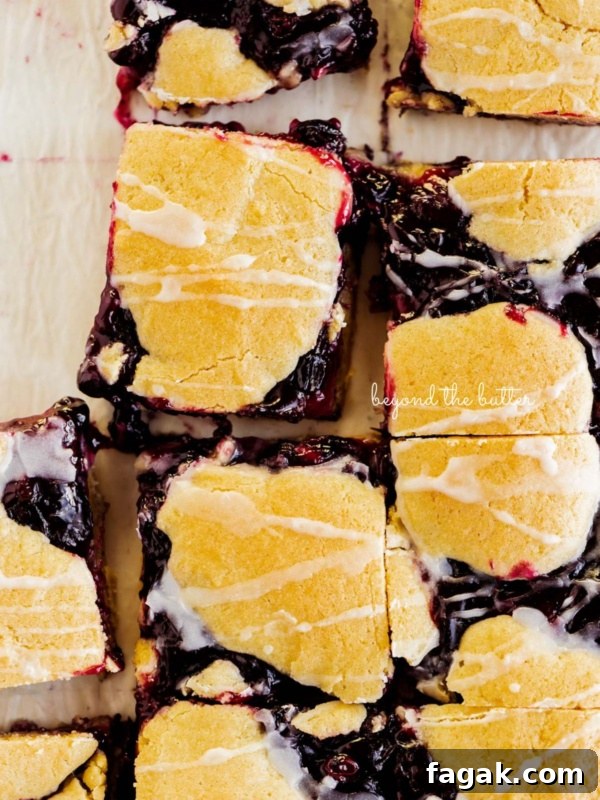 Sliced blueberry swirl coffee cake squares on a white parchment paper background.