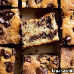 Sliced squares of chocolate chip sour cream coffee cake on brown parchment paper with the center slice on its side.