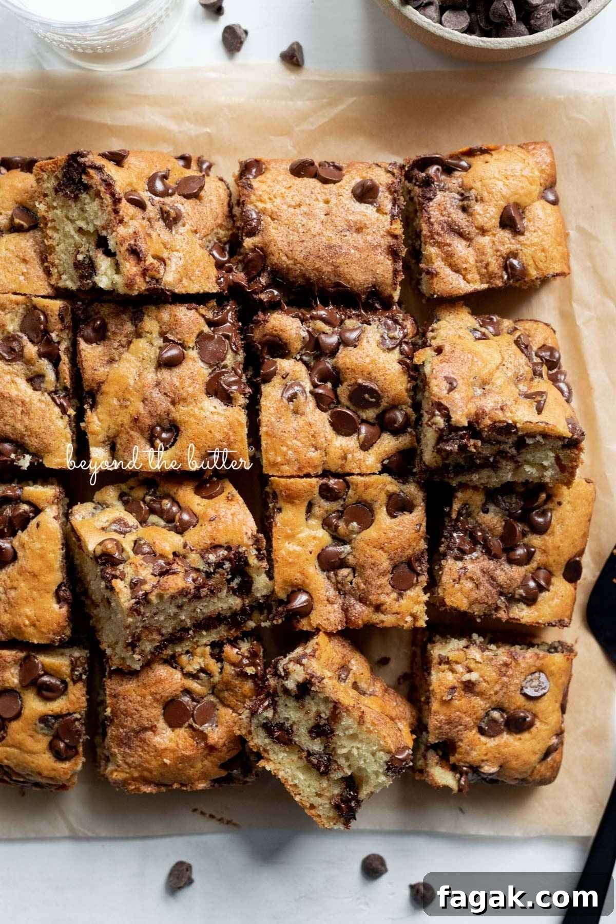 Slices of chocolate chip coffee cake on brown parchment paper with small bowl of chocolate chips placed next to it.