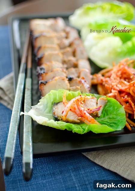 Juicy roasted Korean pork belly is served with spicy onion salad and a pair of chopsticks