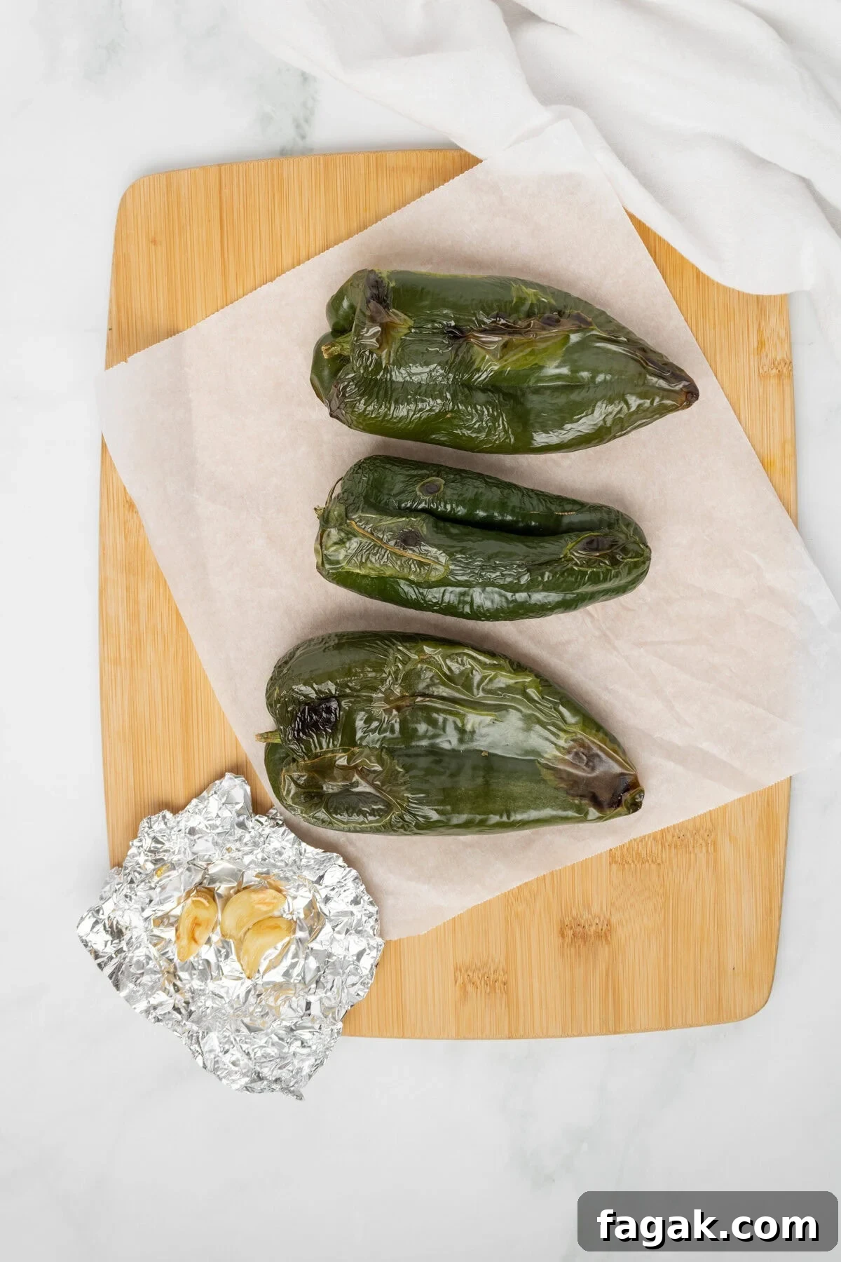 An overhead image of the roasted poblano peppers on a chopping board.