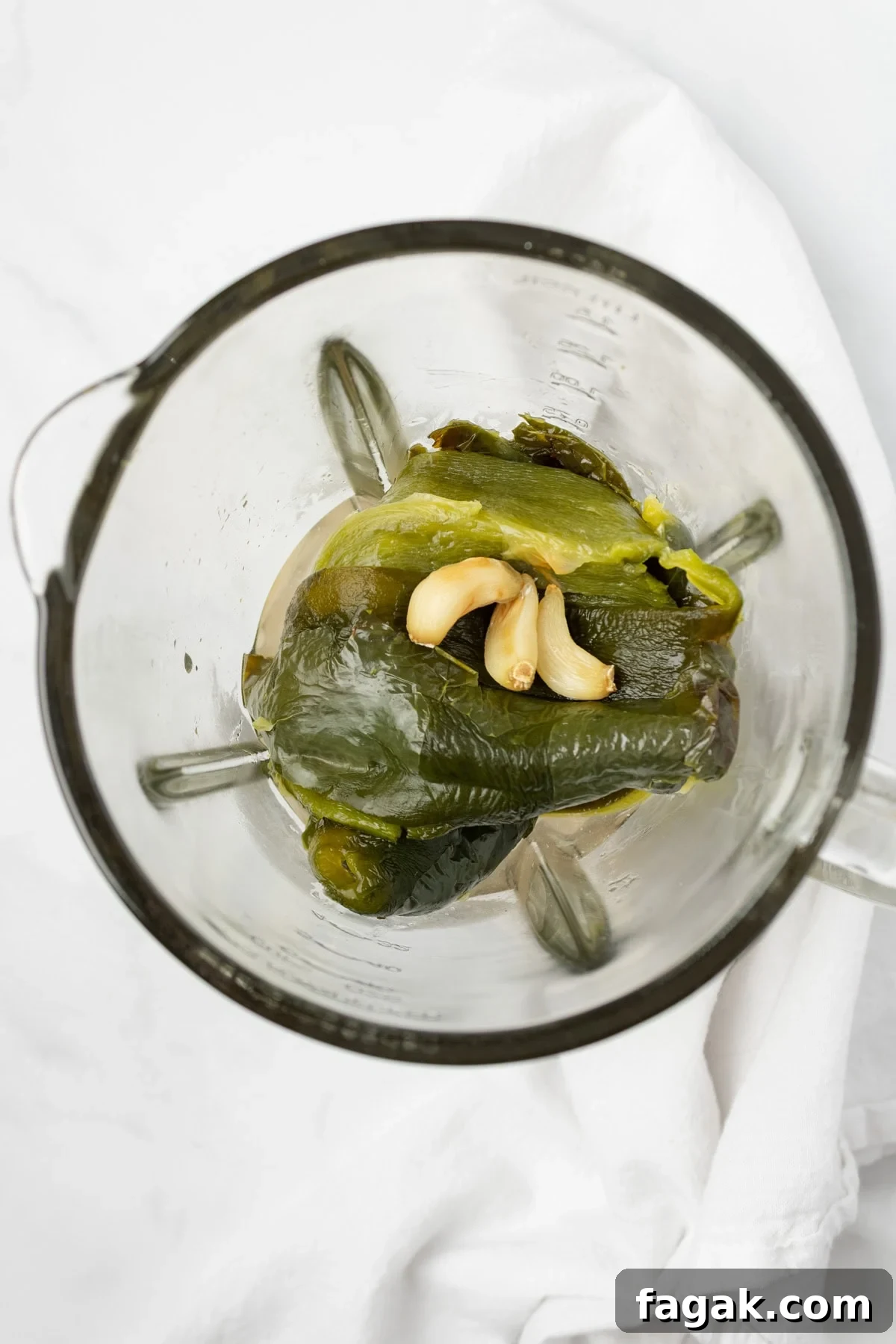 An overhead image of adding the poblano peppers and garlic to the blender.