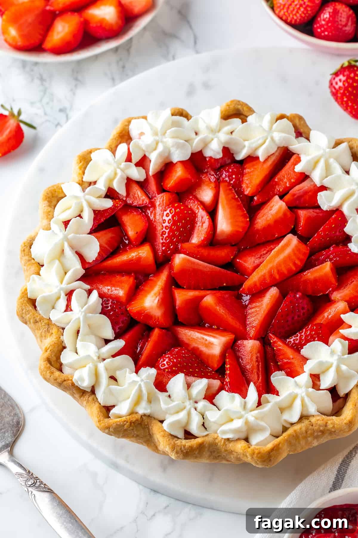 Whole strawberry cream pie surrounded by bowls of fresh strawberries and jam