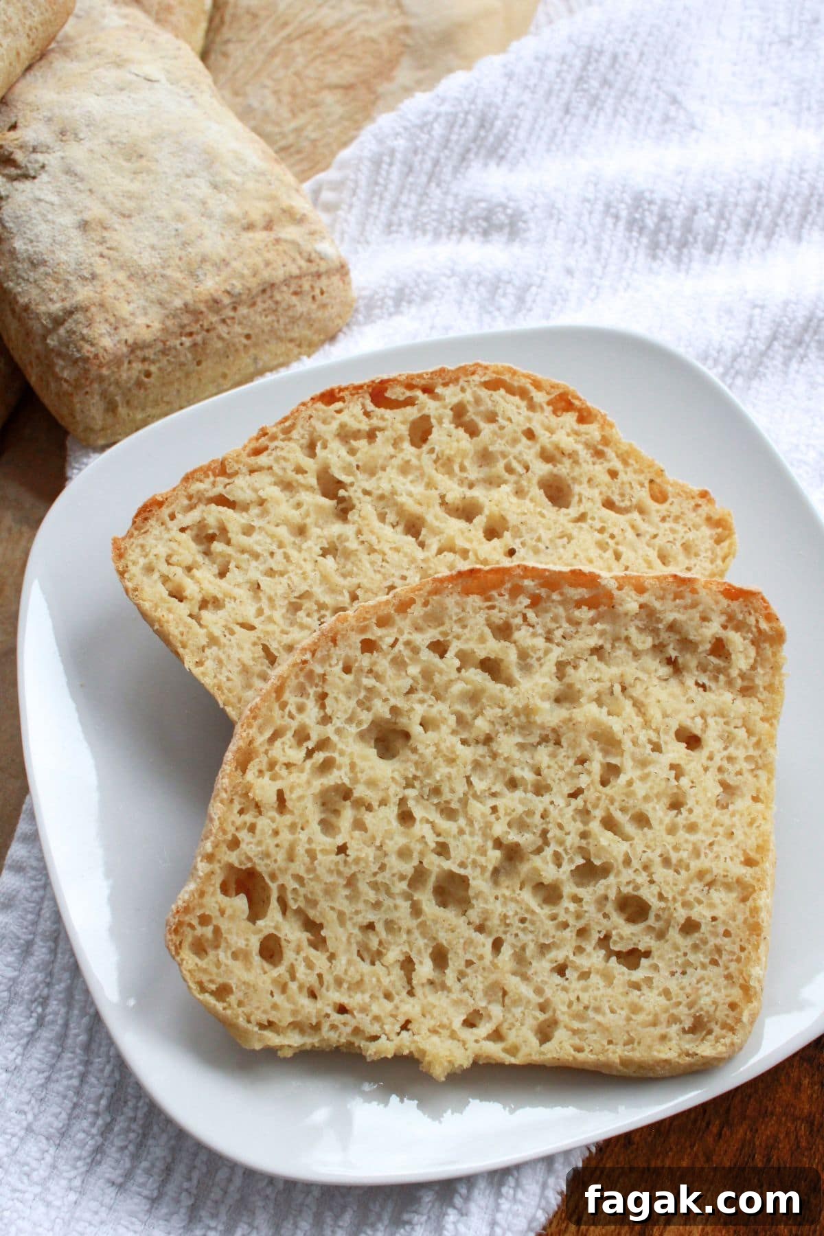 Sliced gluten-free ciabatta buns on white plate.