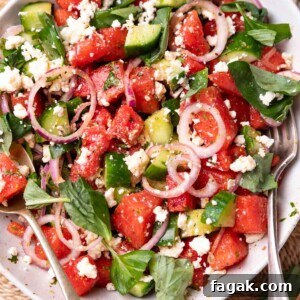 watermelon salad in a white bowl with fork and spoon