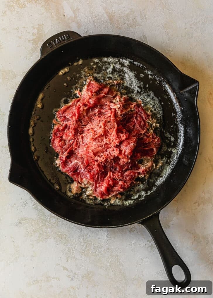 Steak in a cast iron skillet on a tan counter.