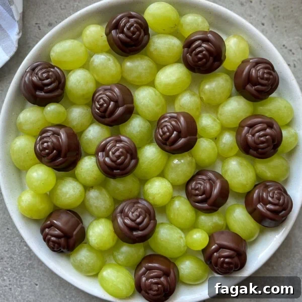 A white bowl filled with green grapes, topped with several chocolate candies shaped like roses, arranged evenly on the surface—perfect for health-conscious bites and creative food recipes.