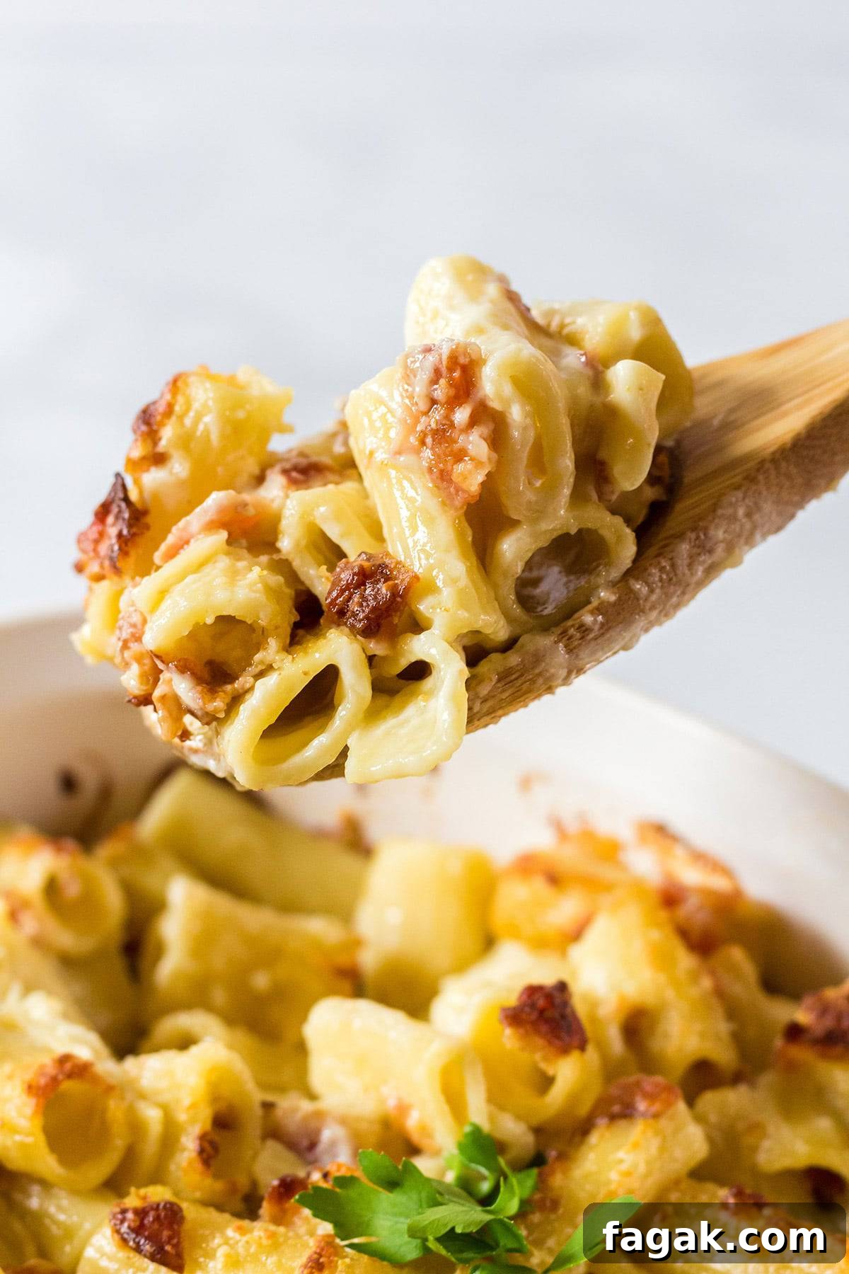 Wooden spoon scooping out bacon mac and cheese from a pan.
