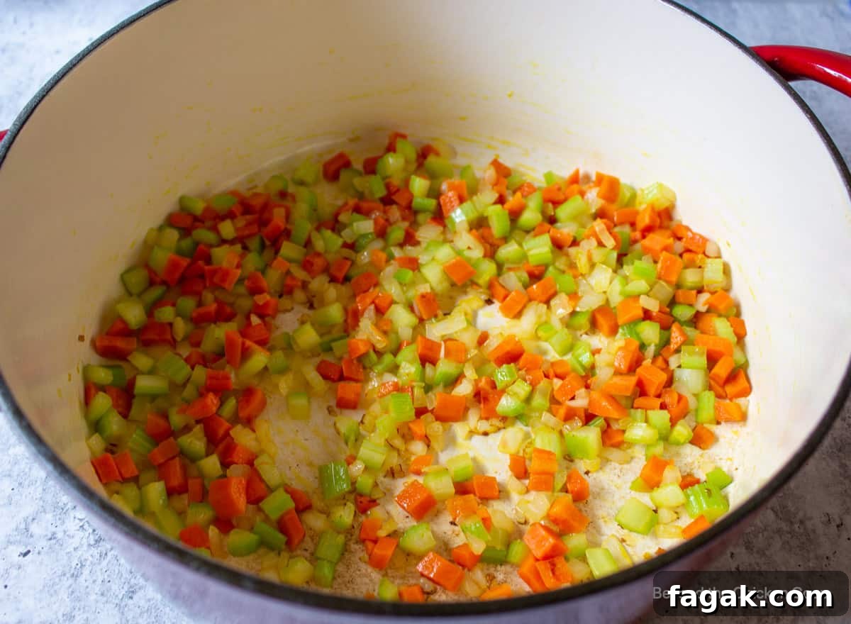 A soup pot with cooked onions, carrots and celery.