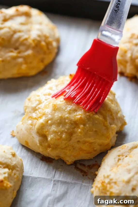 brushing melted butter on a baked biscuit