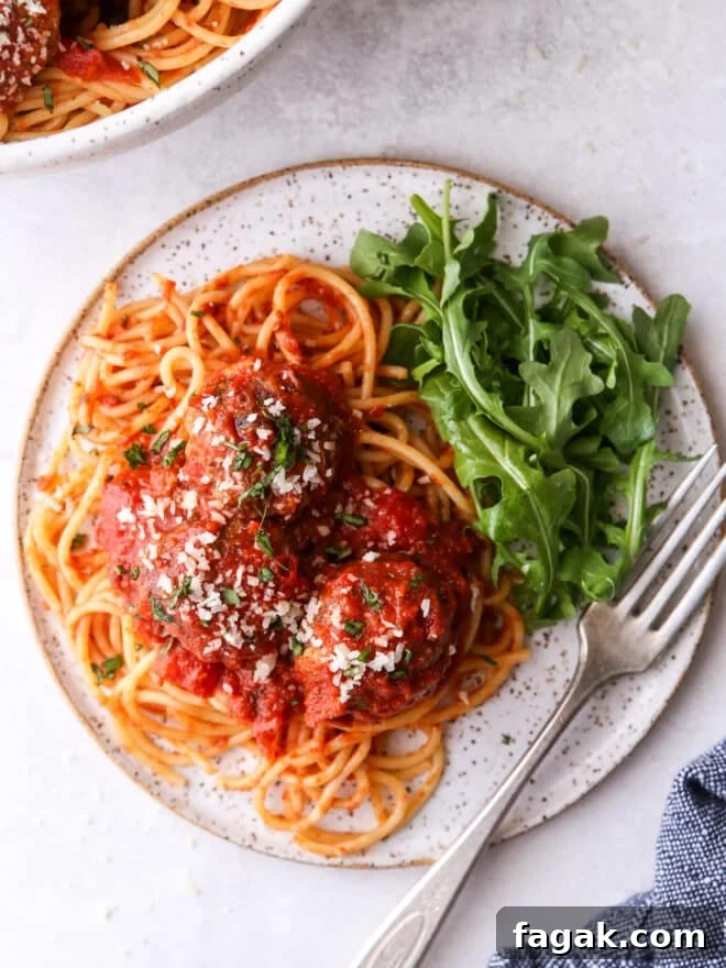 spaghetti and meatballs on a plate with salad
