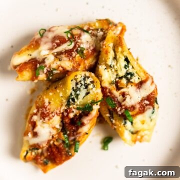 A top down view of three spinach stuffed shells on a plate.