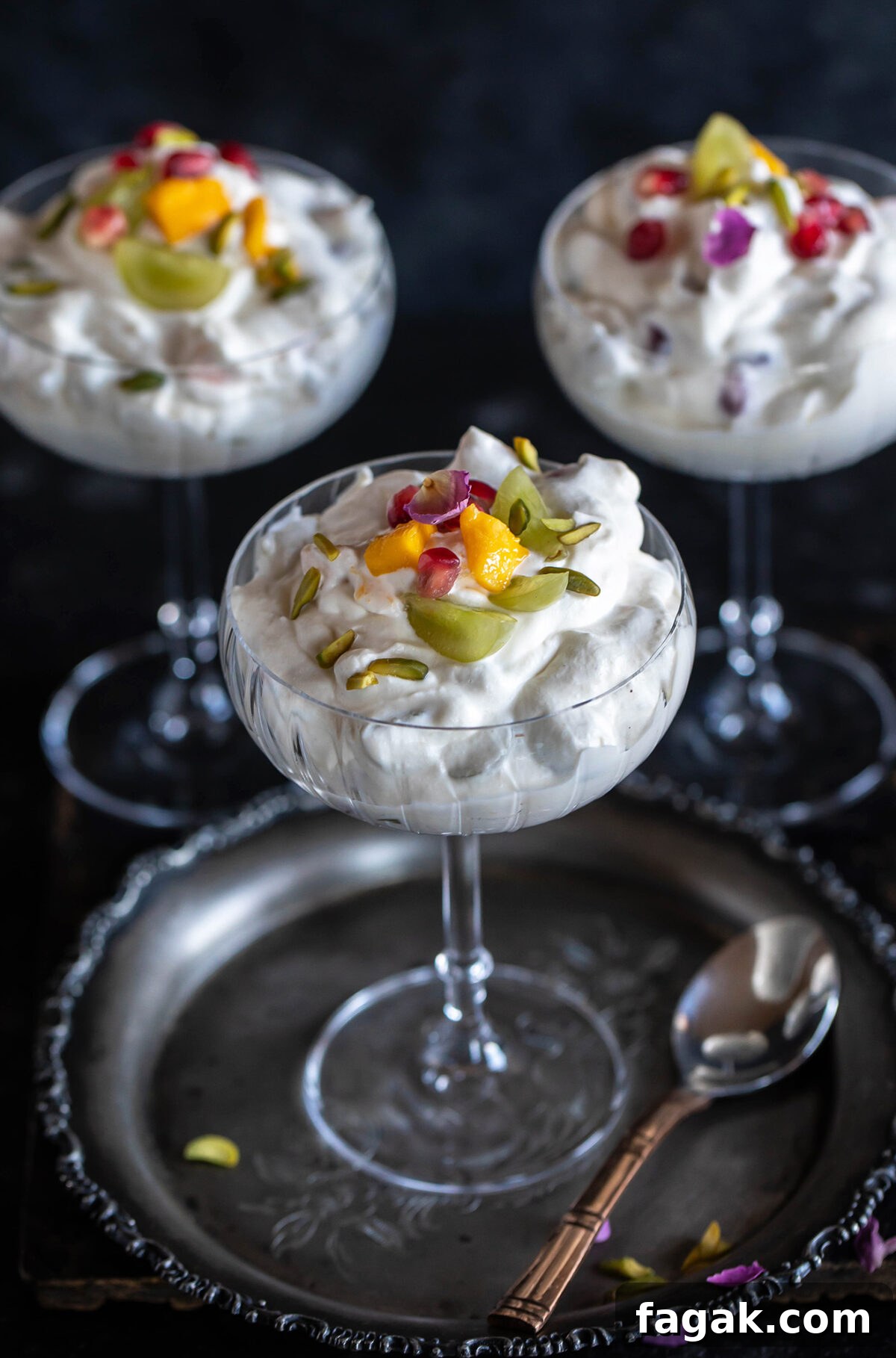 3 glass cups filled with whipped cream and fruits and garnished with rose petal