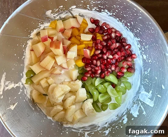 cut apples, grapes, banana, pomegranate seeds added to whipped cream