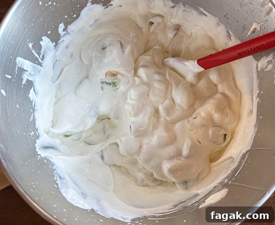 fruits folded into the whipped cream using a red spatula