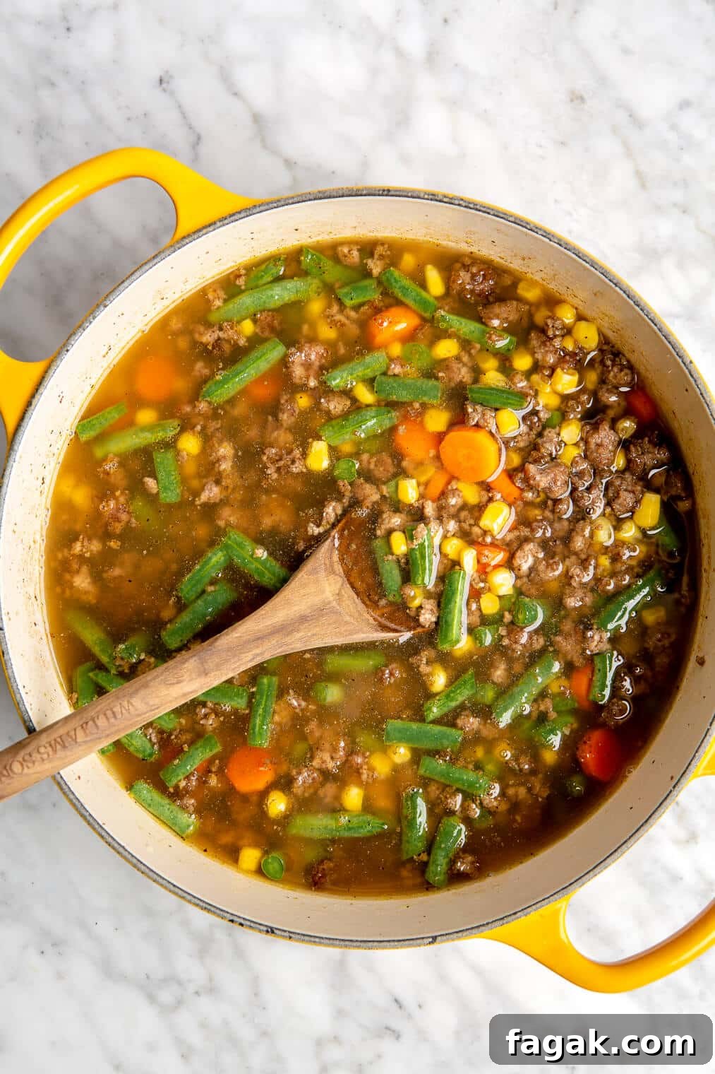 Spoon stirring beef and vegetable soup.