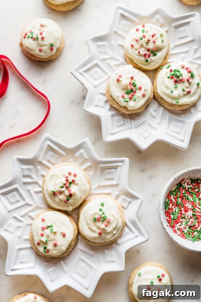 Snowflake plates holding batches of soft frosted eggnog sugar cookies with red and green sprinkles.