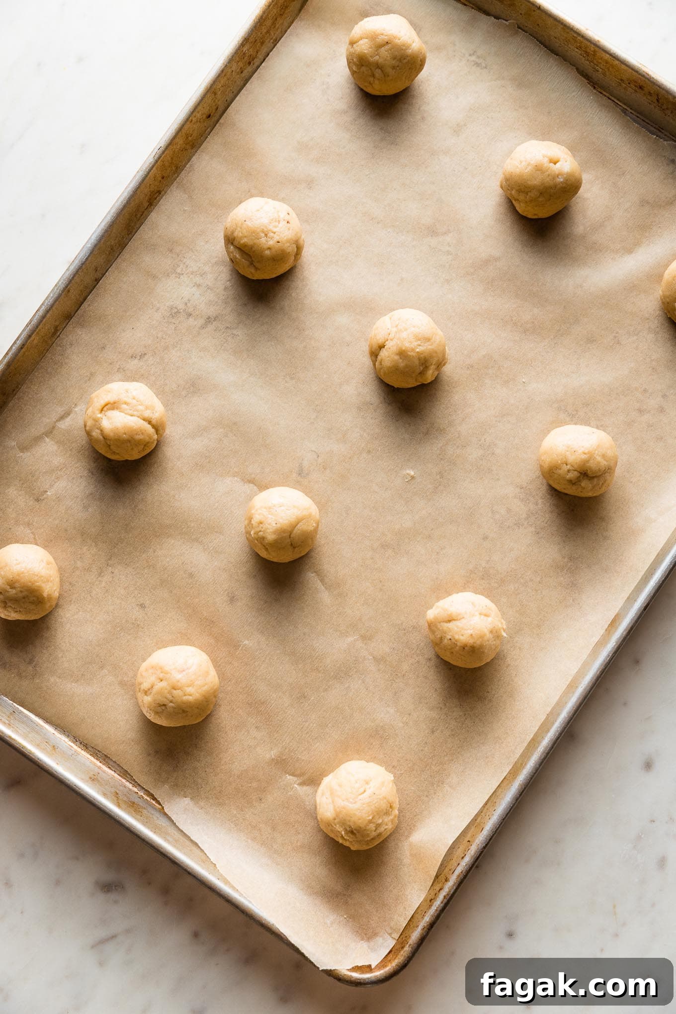 Rolled balls of eggnog sugar cookie dough, ready to bake.