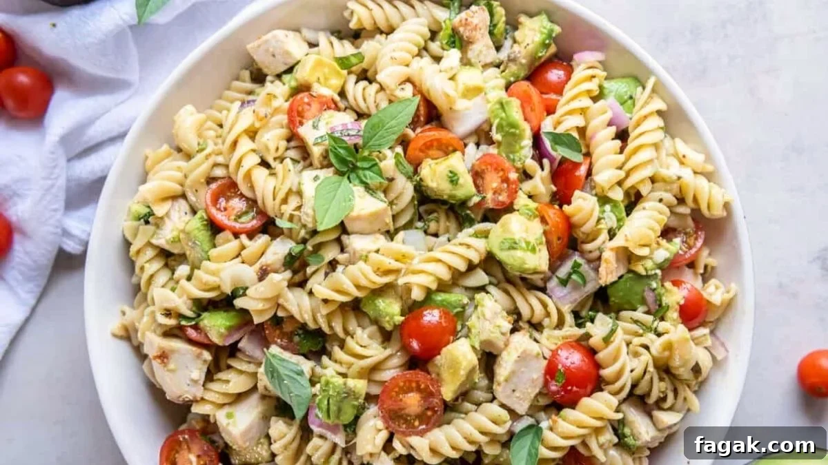 Chicken avocado pasta salad served on a white plate.
