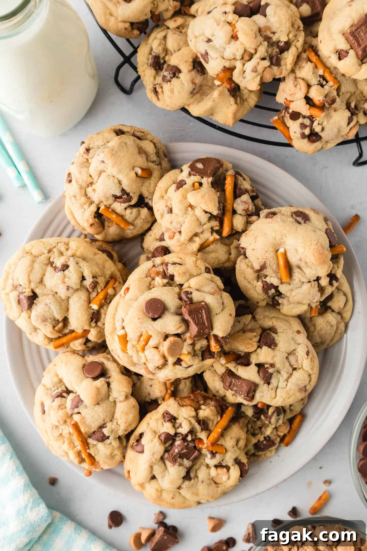 Plate of large kitchen Sink Cookies loaded with chocolate chips, peanut butter chips, toffee bits, caramel bits, and pretzels.