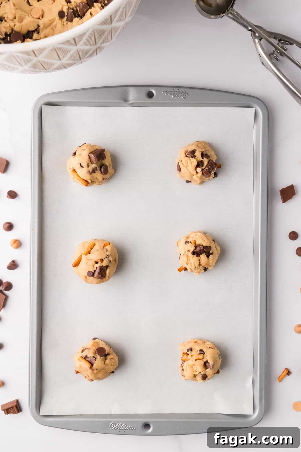 Kitchen sink cookie dough scooped onto lined baking sheet.
