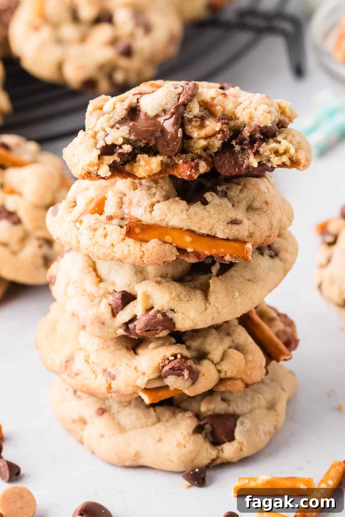 Everything but the kitchen sink cookies stacked on top of one another with a bite taken out of the top cookie to show melted chocolate chips.