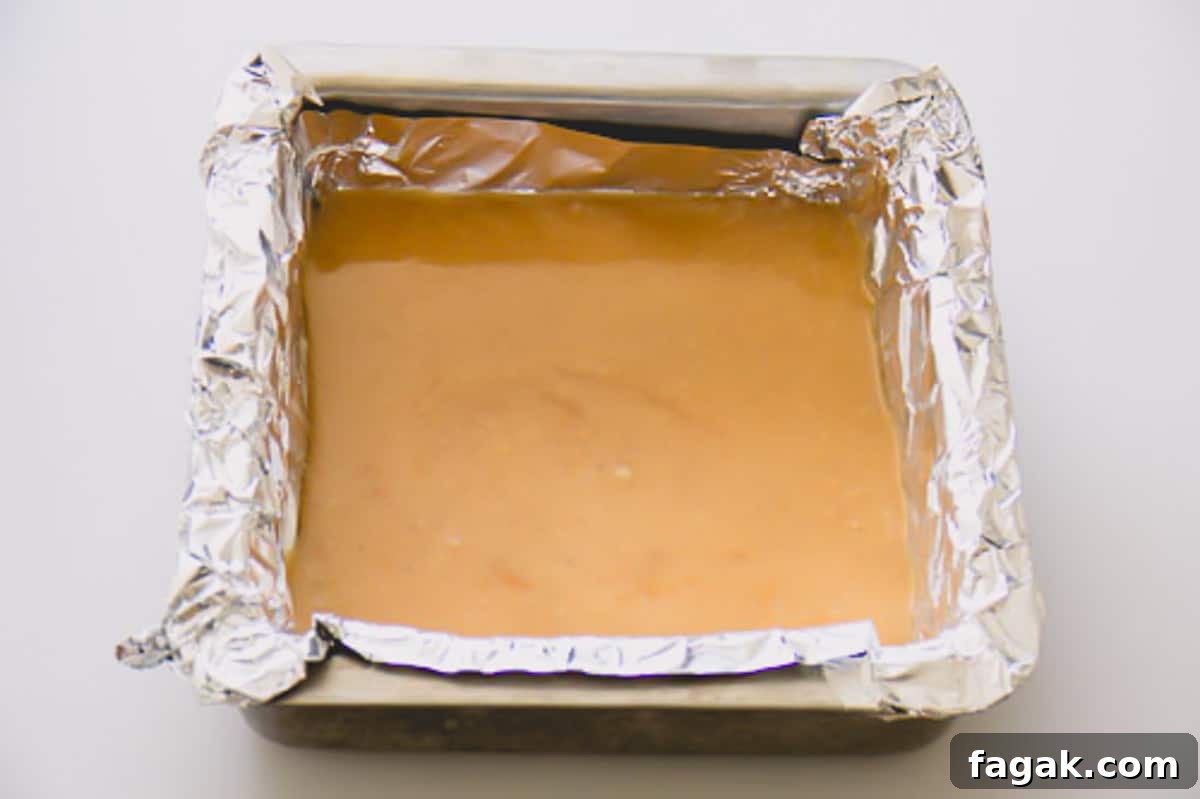 Cardamom caramel candies cooling in a square baking dish lined with aluminum foil.