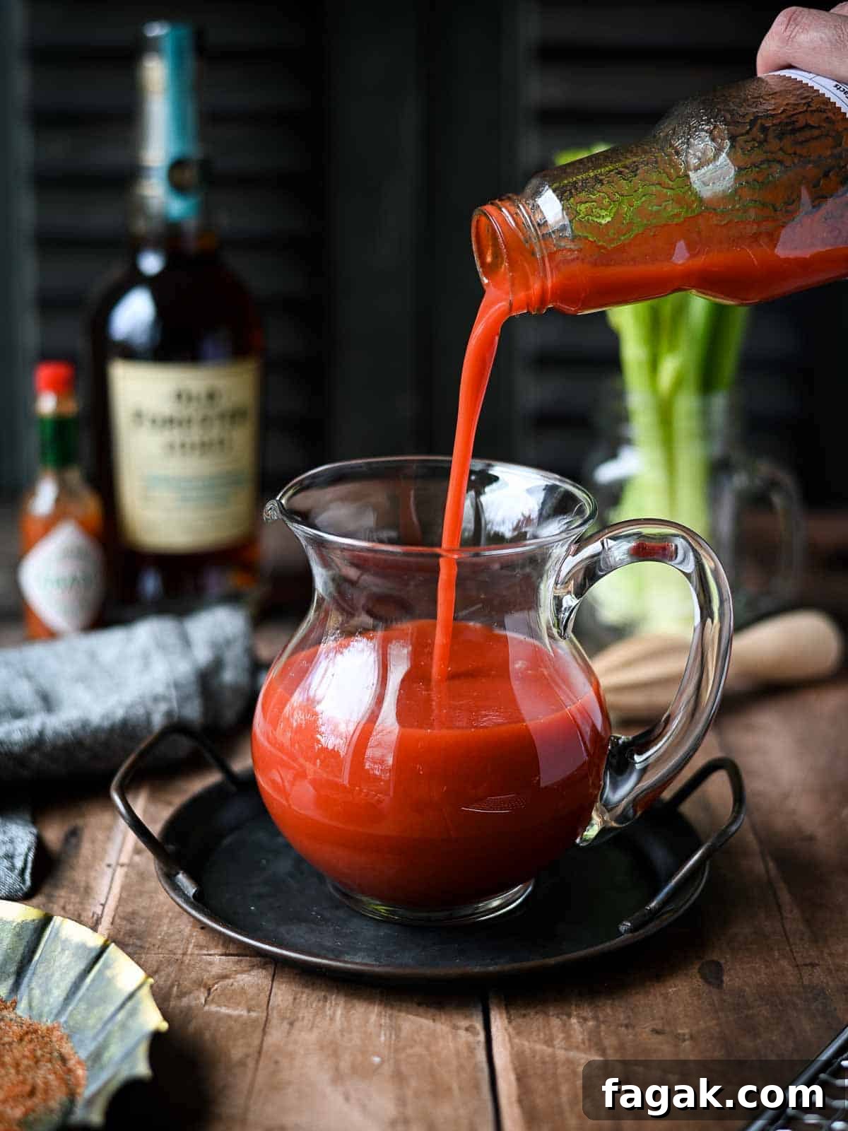 Tomato juice being poured into a clear pitcher.