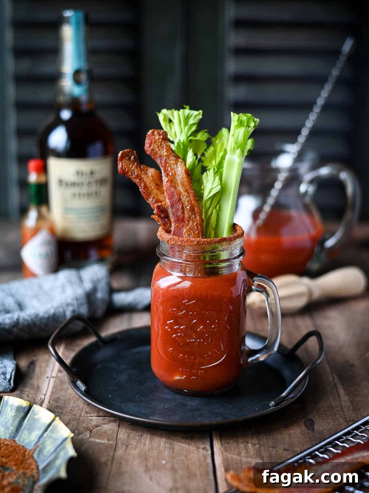 Bourbon bloody mary on a metal tray with celery and bacon.