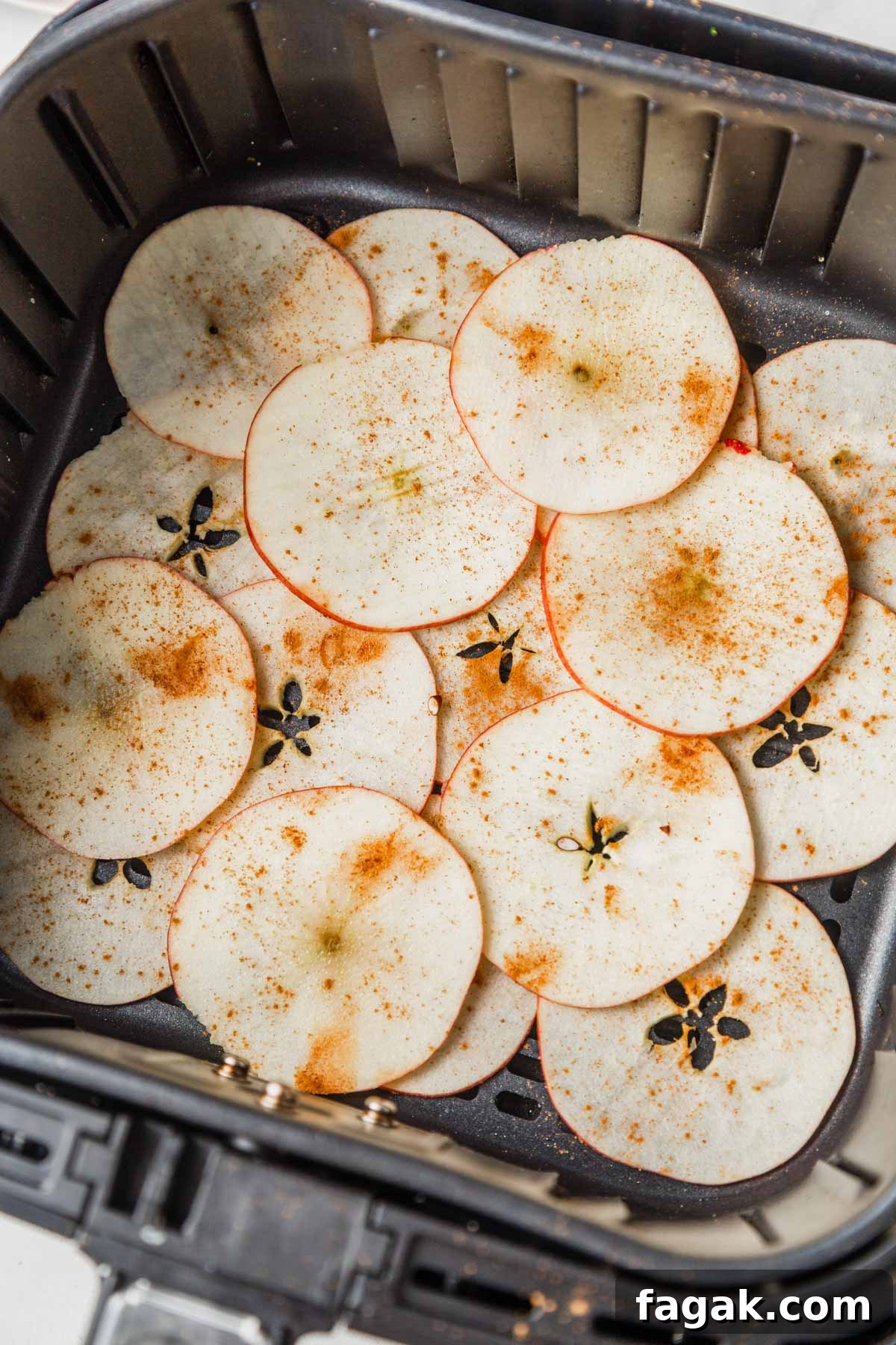 placing the apple slices in the air fryer basket.