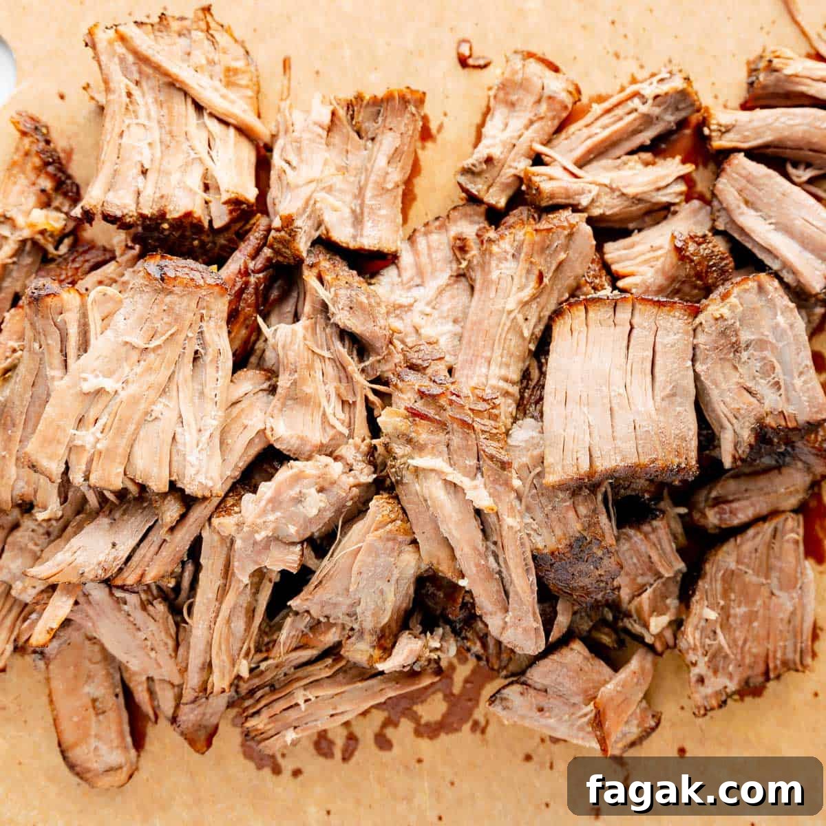 Shredded, cooked meat on a wooden surface.
