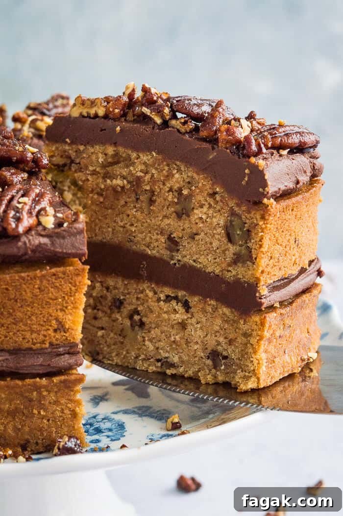 Close up of a slice of vegan, naturally sweetened maple pecan cake with chocolate cashew cream and maple pecans
