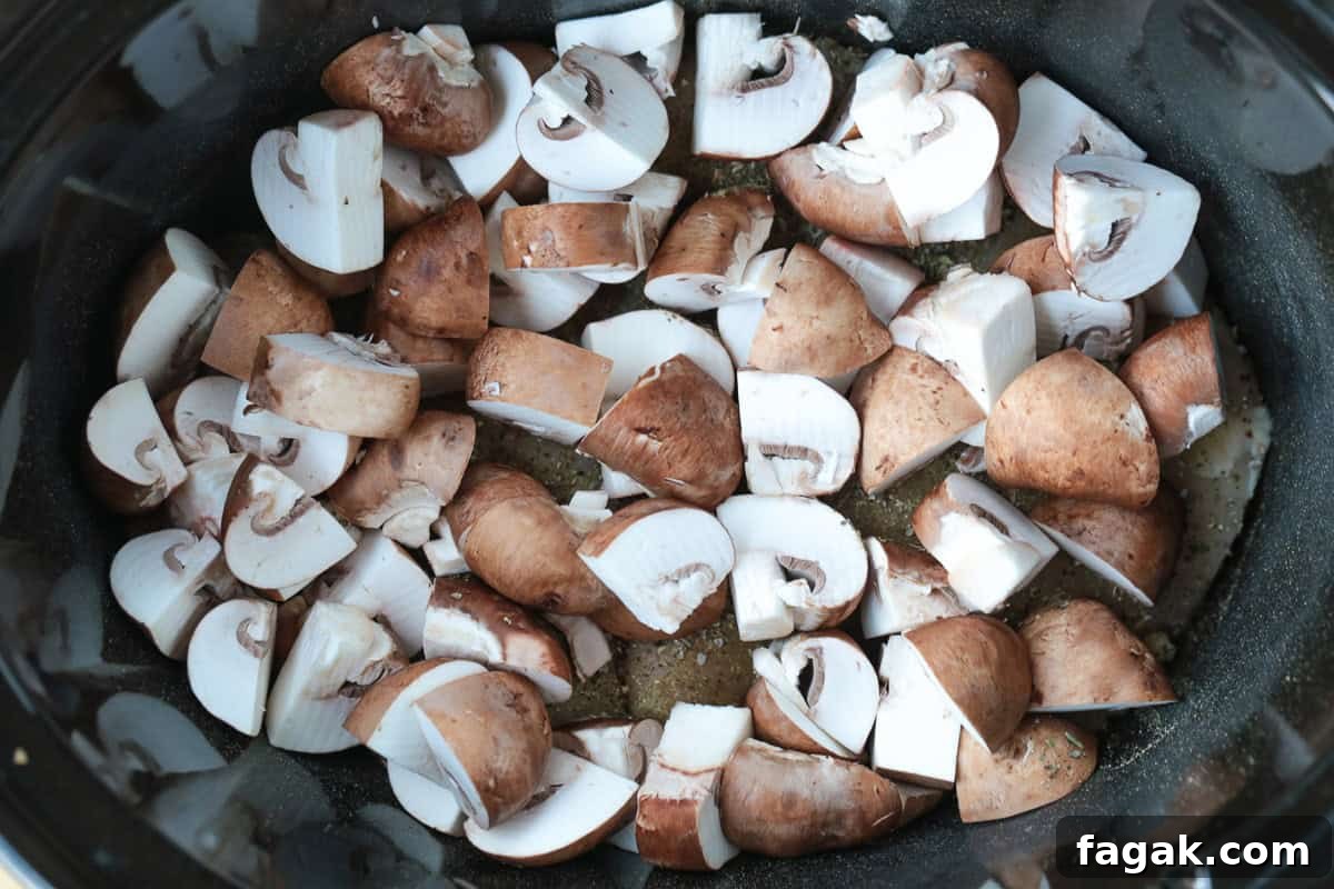 chopped mushrooms in a slow cooker over chicken breasts