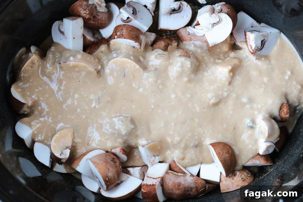 gravy poured over mushrooms and chicken in a crock pot