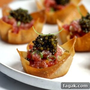 Crispy baked tuna wonton cups filled with raw tuna mixture and finished with caviar, served as an appetizer.