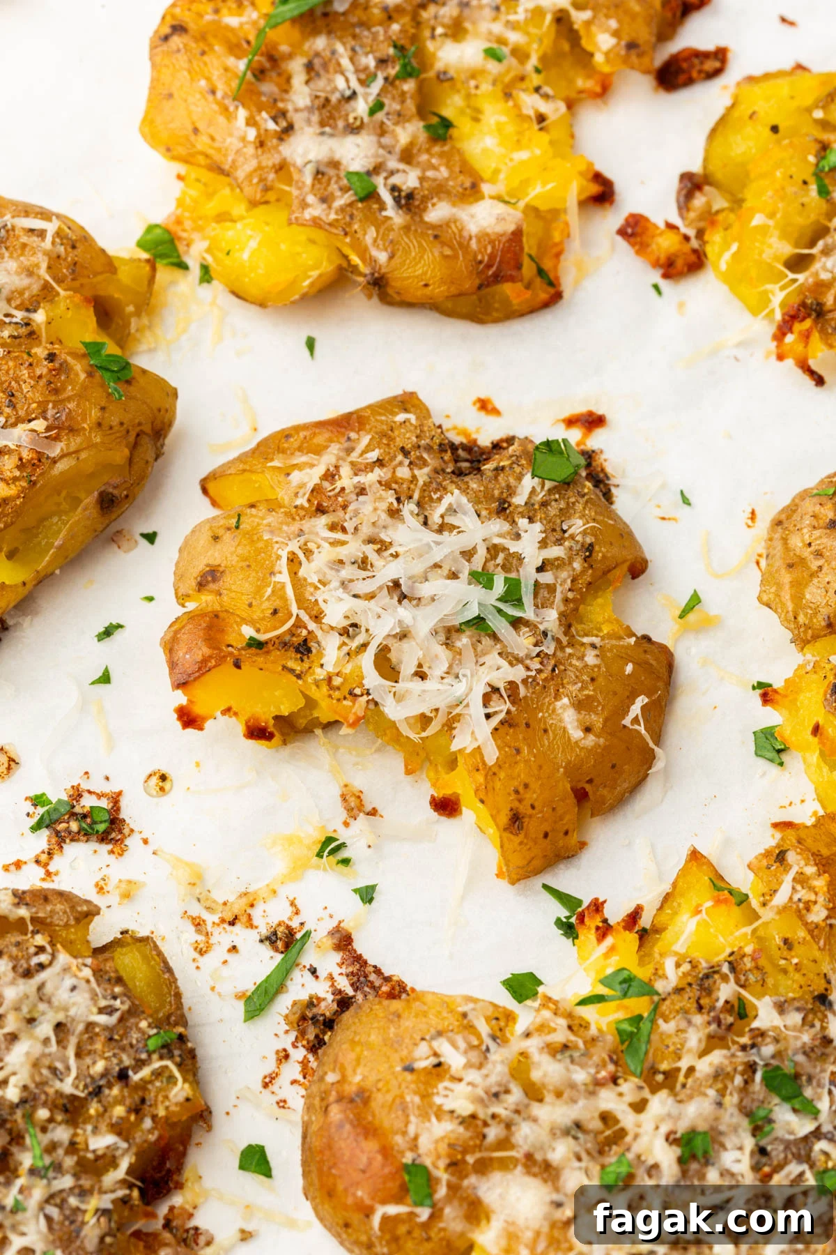 Close-up of a single smashed potato topped with melted parmesan and fresh parsley.