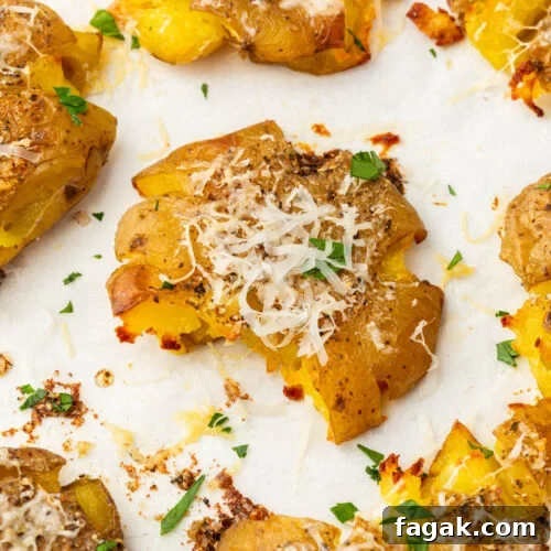 Close-up of a single smashed potato topped with melted parmesan and fresh parsley.